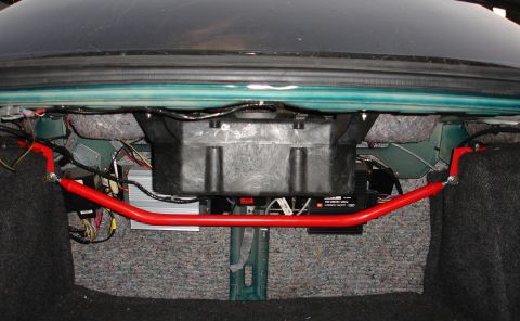 1993 Ford Taurus - Aftermarket rear strut tower brace installed in the trunk of a vehicle, with a subwoofer enclosure visible.