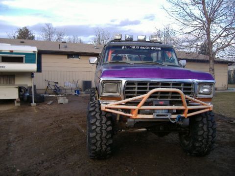 1979 Ford Bronco - A modified 1979 Ford Bronco sits in a dirt lot with a camper and bicycle nearby.