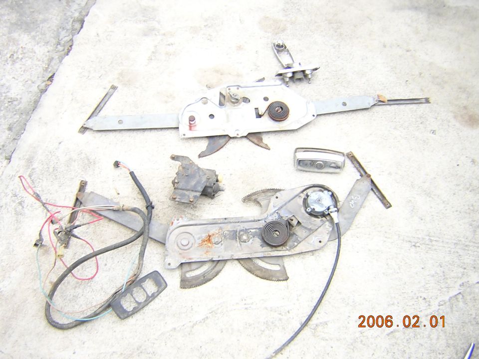 Car window regulators and some associated parts laid out on concrete