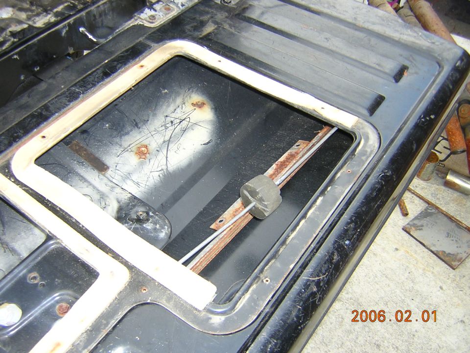 Interior of a tailgate with a removed window frame and visible rust