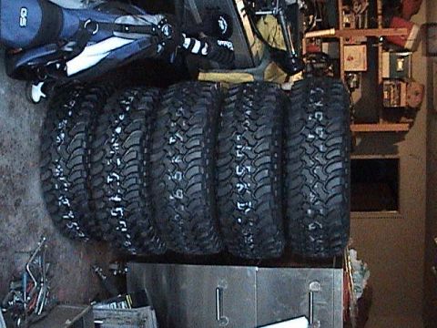 1994 Ford Bronco - A set of five aggressive off-road tires are neatly stacked, ready for adventure.