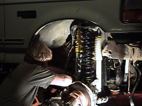 1994 Ford Bronco - Mechanic works on the front suspension of a 1994 Ford Bronco during a 6-inch lift and Sky Shackle Flip installation.