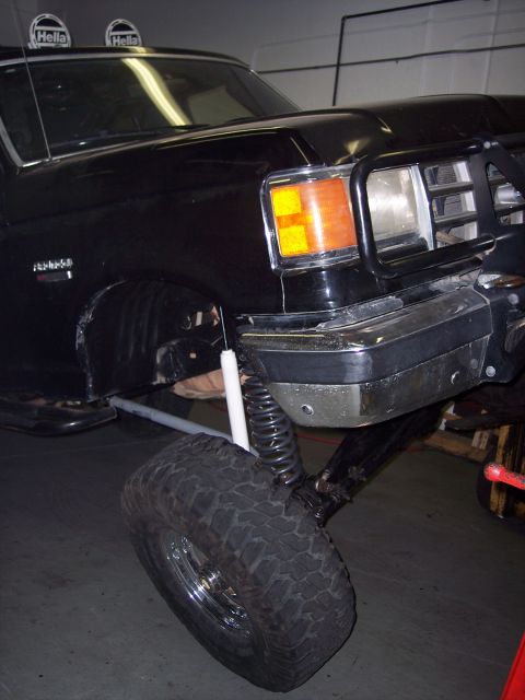 1988 Ford Bronco - Black Ford Bronco with lifted suspension and chrome bumper, viewed from the front three-quarter angle.
