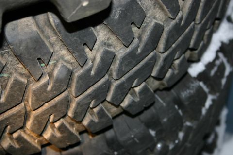 2003 Jeep TJ - The aggressive tread pattern of a tire is visible, with a dusting of snow on its sidewall.