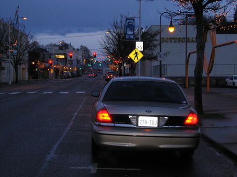 1999 Ford Crown Victoria - A gold Ford Crown Victoria is parked on a street as dusk settles and streetlights begin to illuminate the scene.
