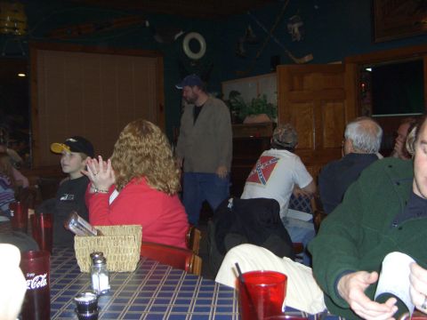 1996 Ford Bronco - A group of people are seated at tables in a restaurant, with one individual prominently displaying a confederate flag on their shirt.