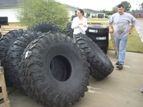 1996 Ford Bronco - A collection of heavy-duty tires is displayed outdoors, with two individuals observing them.