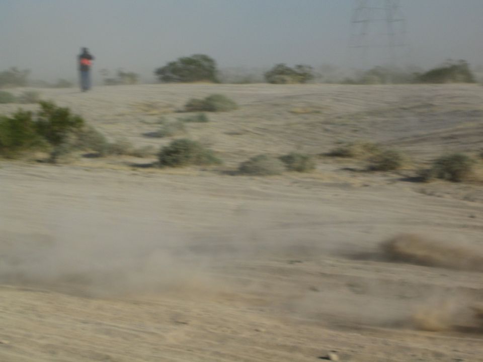 Hazy dusty desert wash with a person standing in the distance and a power tower