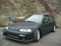 1995 Ford F-150 - A matte black hatchback is parked outdoors with a rocky background.