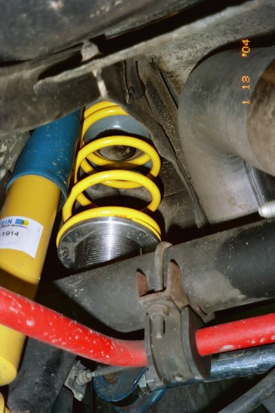 1997 Ford Crown Victoria - This image shows aftermarket suspension parts, including a yellow coilover and a red sway bar, mounted to a vehicle's chassis.