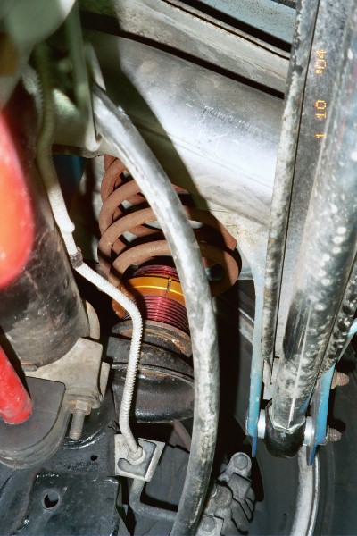 1997 Ford Crown Victoria - Undercarriage view of a vehicle's suspension system, showing a worn coilover shock absorber.