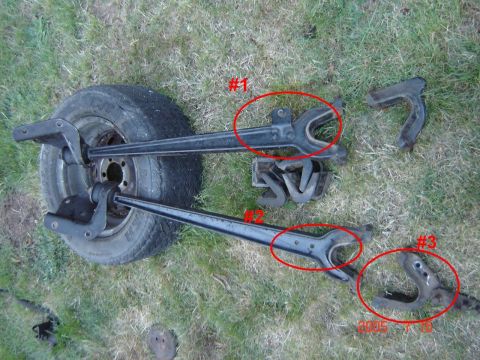 1993 Ford Bronco - Close-up view of disassembled axle components and a tire on a grassy surface.