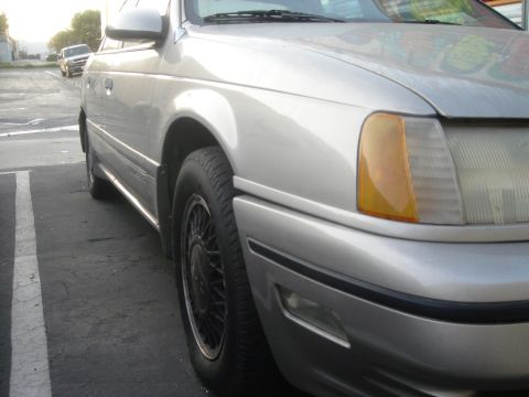 1991 Ford Taurus - Silver 1991 Ford Taurus parked on asphalt with another vehicle in the background.