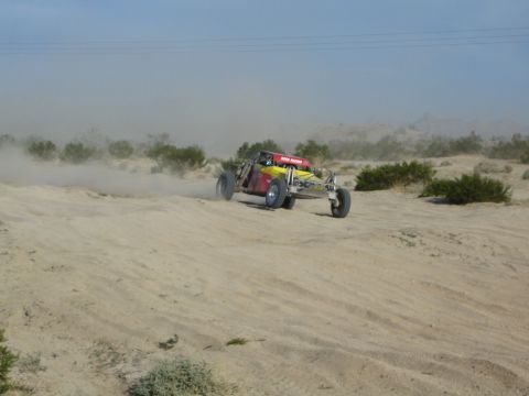 Red and yellow off-road buggy at speed throwing sand in the desert