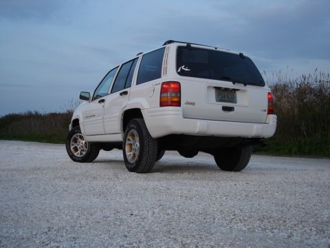 1997 Jeep Grand Cherokee - This white Jeep Grand Cherokee is seen from the rear on a gravel road with dry grass in the background.