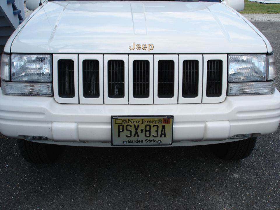 White Jeep Grand Cherokee front end with seven-slot grille and New Jersey plate