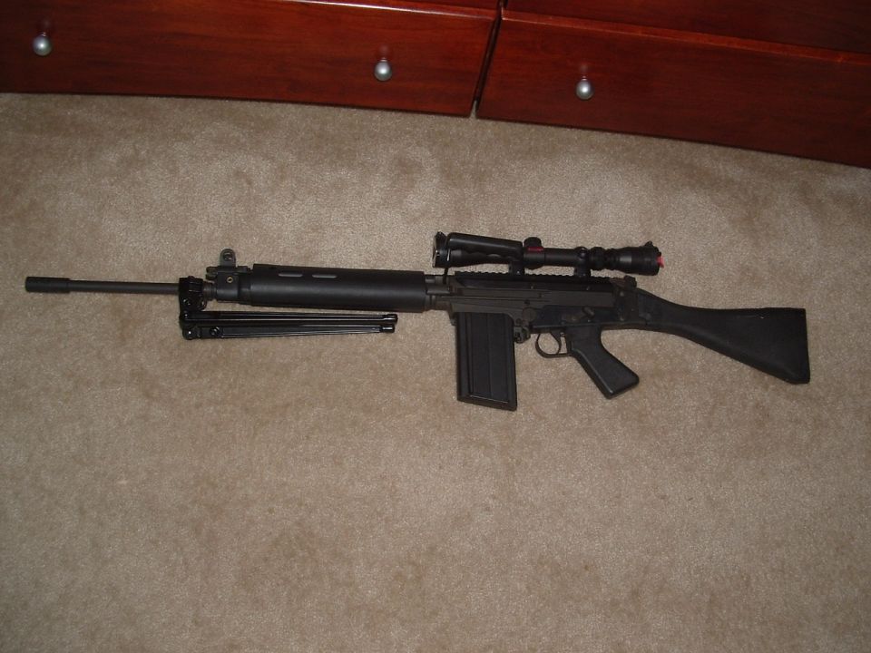 Assault rifle with scope and bipod on carpet, in front of wooden furniture