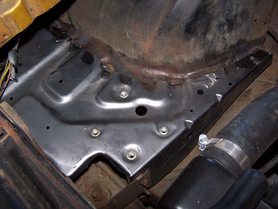 Newly welded bare-metal sheetmetal panel in an engine bay during restoration