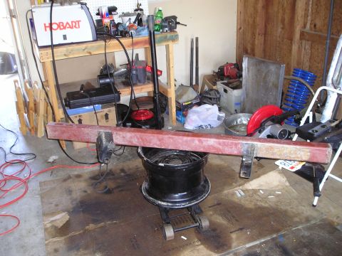 1986 Ford Bronco II - A custom bumper is supported by a jack and a tire in a cluttered garage setting.