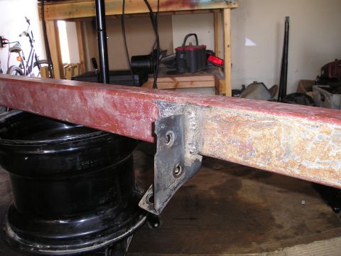 1986 Ford Bronco II - Close-up of a red metal bumper part with a black mounting bracket, resting on a black wheel rim.