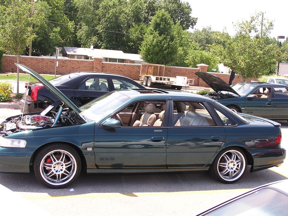 Green 1993 Ford Taurus sedan with hood open, tan interior, and aftermarket wheels