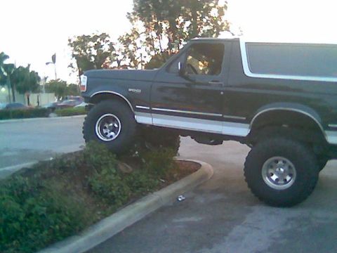 1992 Ford Bronco - A 1992 Ford Bronco is shown with its front tires on a curb and its rear tires on the pavement.