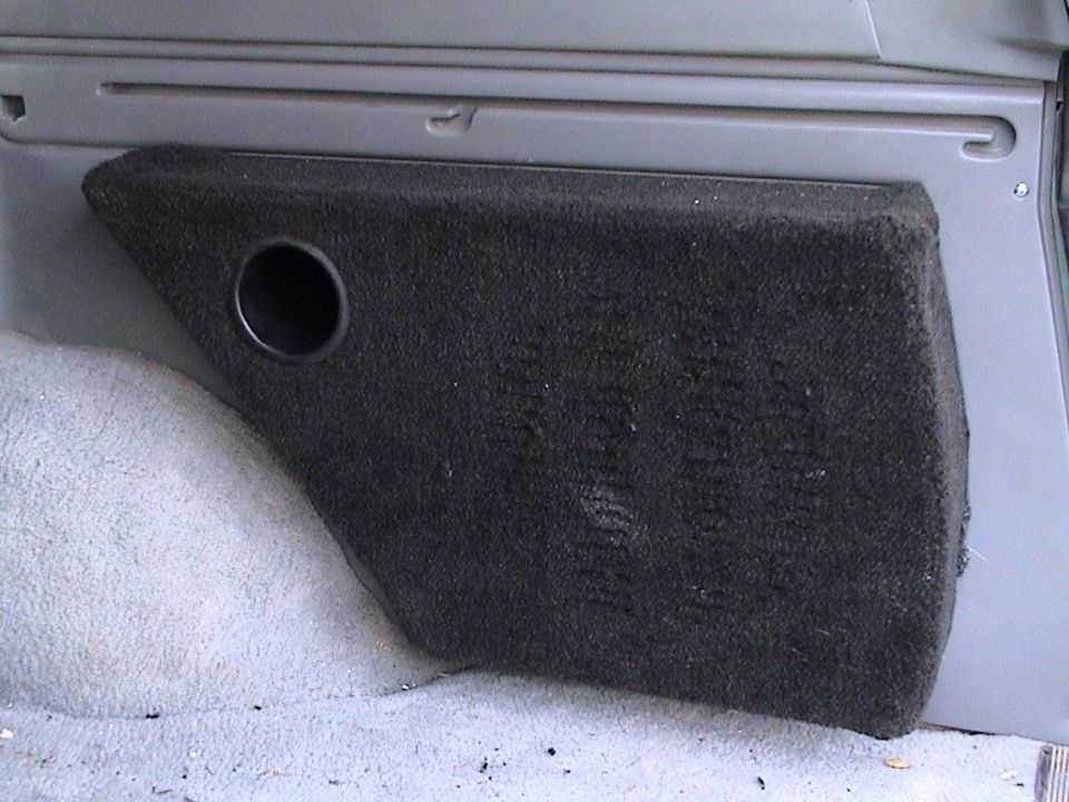 Gray carpeted rear interior trim panel with a round speaker cutout hole