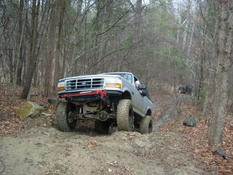1995 Ford Bronco - Ford Bronco tackling a challenging muddy off-road course with a second vehicle visible.
