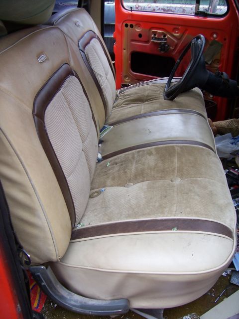 1978 Ford Bronco - The interior of a vehicle shows a worn bench seat and the exposed door frame.