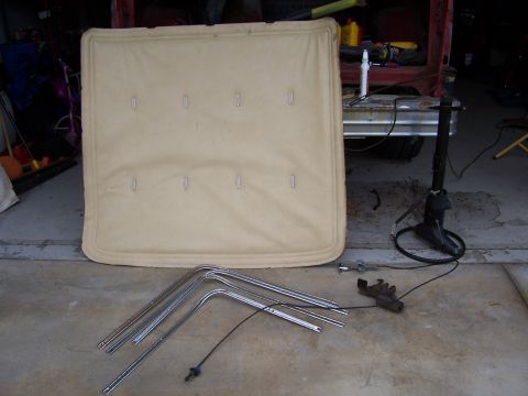 1978 Ford Bronco - Tan headliner and chrome trim pieces are laid out on a concrete floor, possibly for a vehicle restoration project.