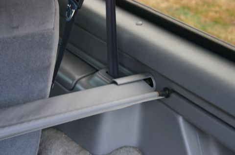 1994 Ford Bronco - The interior of a vehicle shows a retracted cargo cover and a seatbelt mechanism.