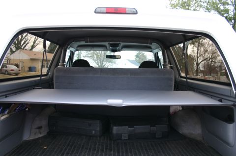 1994 Ford Bronco - The interior of a 1994 Ford Bronco shows the cargo cover extended over two cases in the rear storage area.