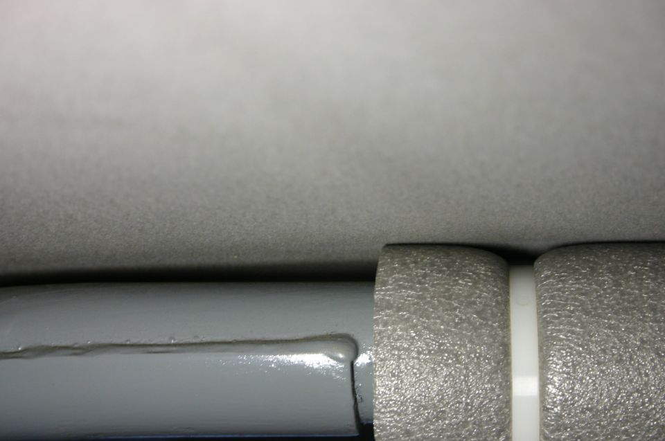 Macro detail of grey headliner fabric, glossy grey painted bar and textured plastic trim