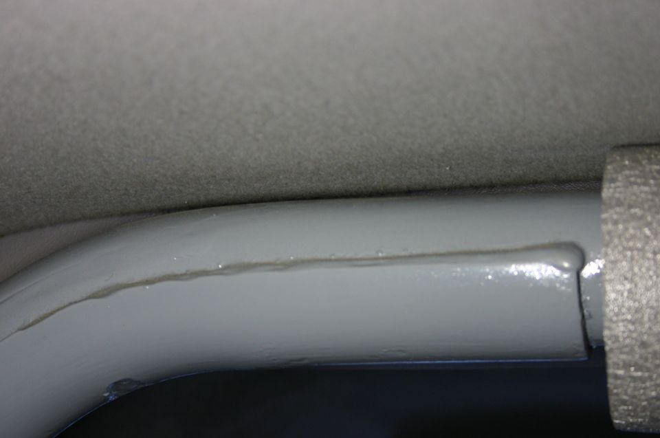 Close-up of a grey painted interior tube against grey headliner with foam pad