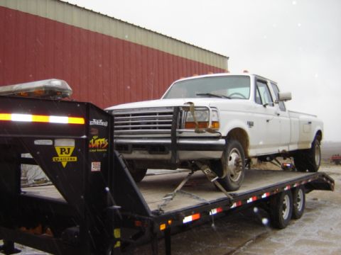 1992 Ford Bronco - A white dually pickup truck is being transported on a flatbed trailer.