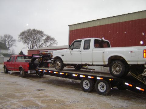 1992 Ford Bronco - A white 1992 Ford F-350 Dually pickup truck is being transported on a trailer, with a red pickup truck in the background.