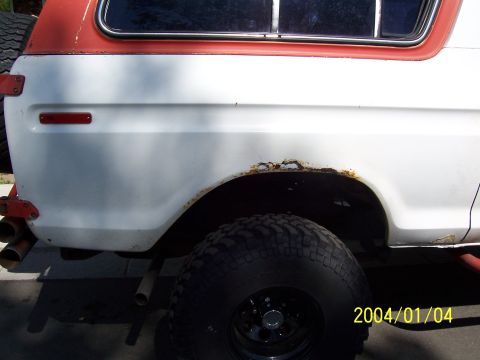 1978 Ford Bronco - The rear quarter panel of a 1978 Ford Bronco shows significant rust damage around the wheel well.