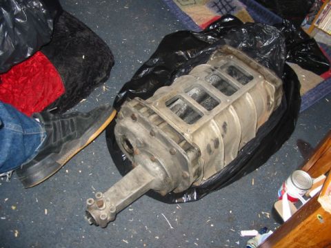 1985 Ford Crown Victoria LTD - A supercharger is shown, partially covered in a black plastic bag, on a carpeted floor.