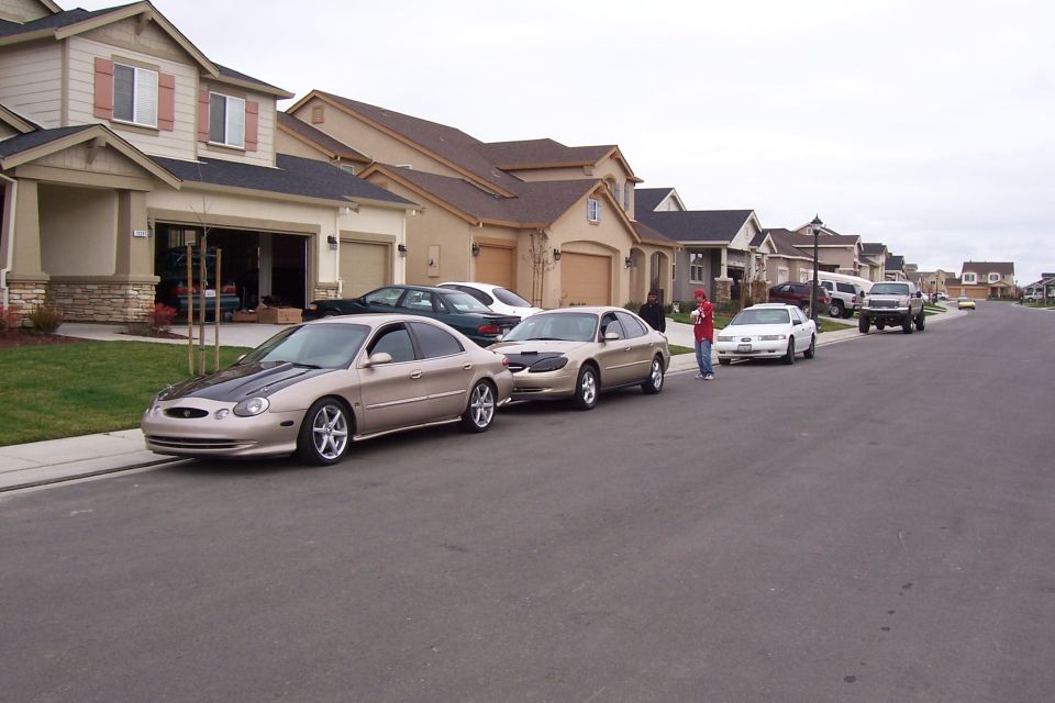 1998 Mercury Sable with aftermarket black hood parked on suburban street, other cars visible