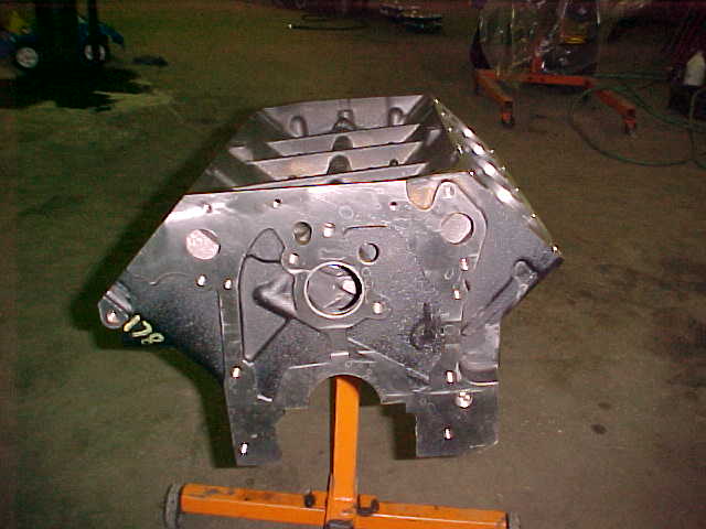 Bare metal engine casting on orange shop stand in a garage