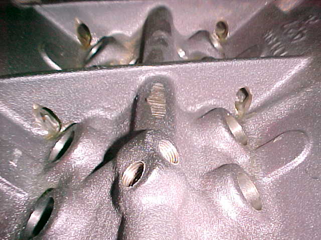 Close-up of cast aluminum engine part with threaded holes and studs