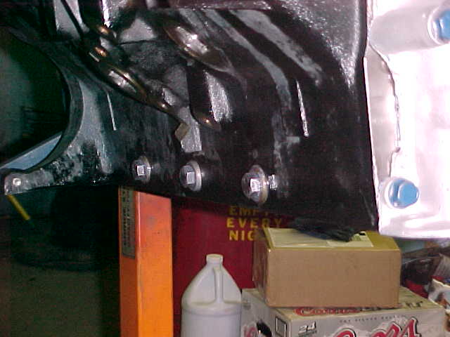 Black transmission bellhousing casting with bolts, in a cluttered garage