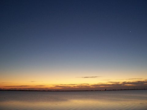 1994 Ford Probe - Sunset over the water with a distant city skyline visible on the horizon.