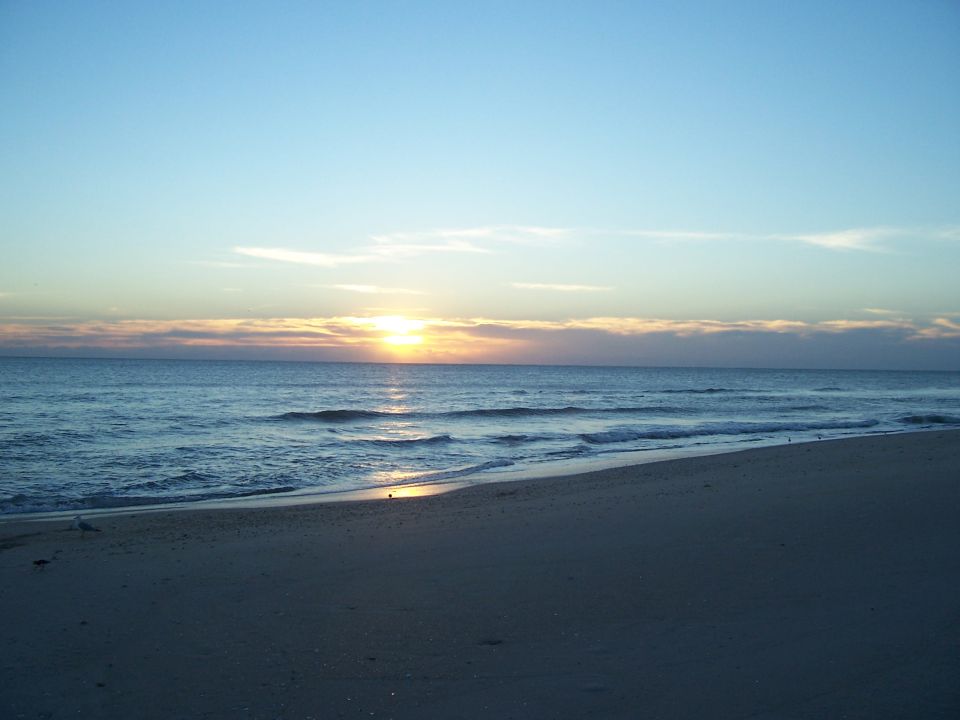 Sunrise over the ocean with waves on the beach. Supermotors logo in corner