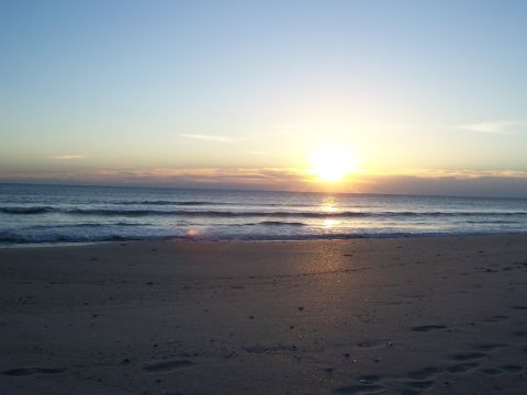 1994 Ford Probe - The sun dips below the horizon, casting a warm glow over the ocean and sandy shore.