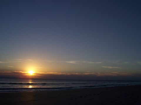 1994 Ford Probe - A tranquil beach scene unfolds as the sun dips below the horizon, casting a warm glow over the ocean.