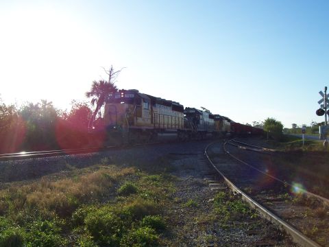 1994 Ford Probe - Multiple locomotives pull a train along railroad tracks under a clear blue sky.