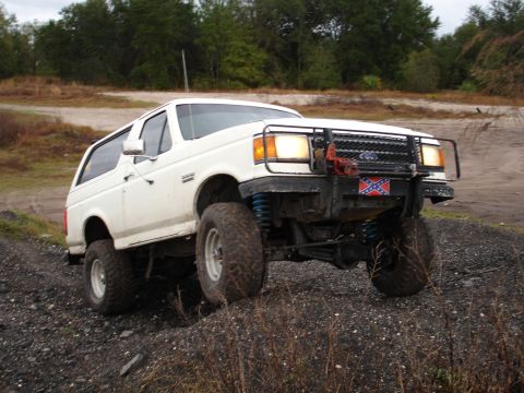 1989 Ford Bronco - 1989 Ford Bronco navigates rough terrain with its lifted suspension and aggressive tires.