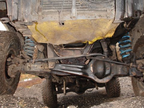 1989 Ford Bronco - Undercarriage of a 4x4 vehicle, focusing on suspension and drivetrain components. Visible watermark: SUPERMOTORS.