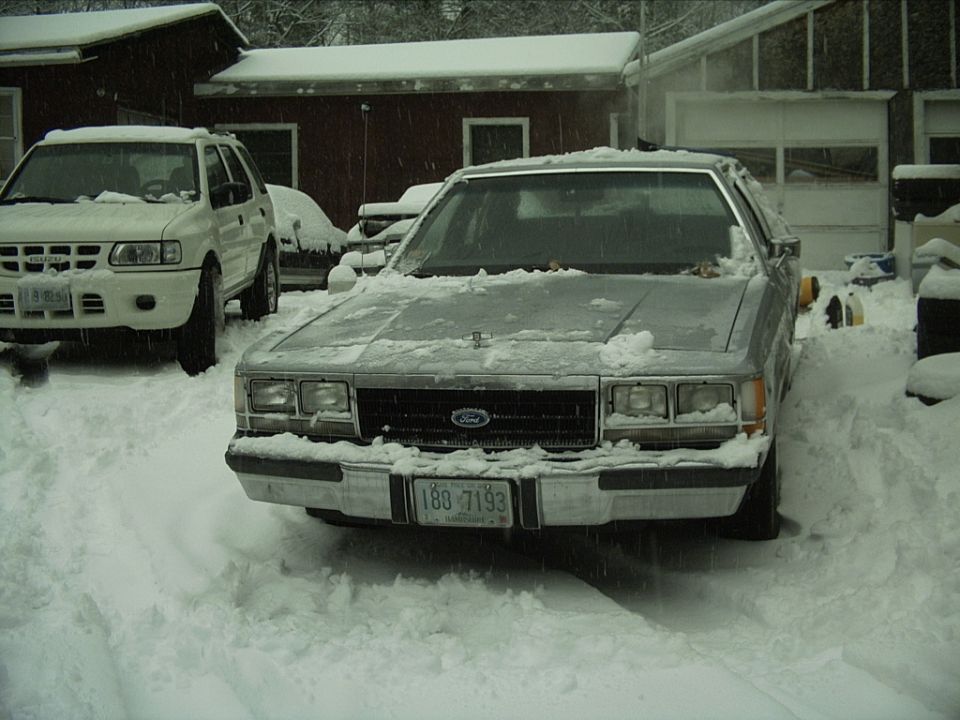 Silver sedan in snow, front view. License plate 188 7193